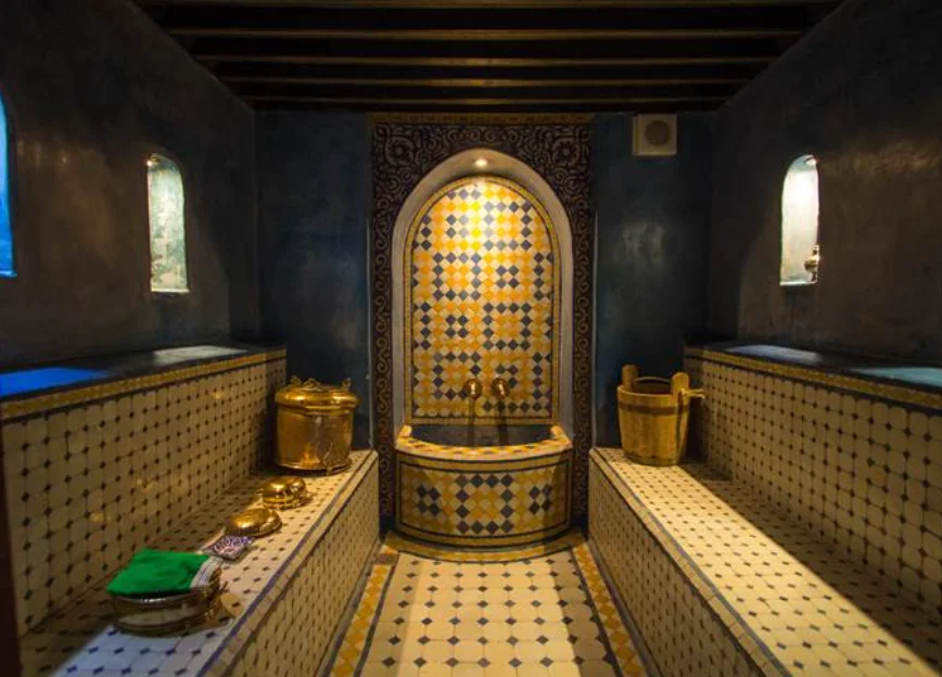 Intérieur d'un hammam à Fès dans la médina avec de la vapeur, des mosaïques traditionnelles, du savon noir et un gant de gommage kese.