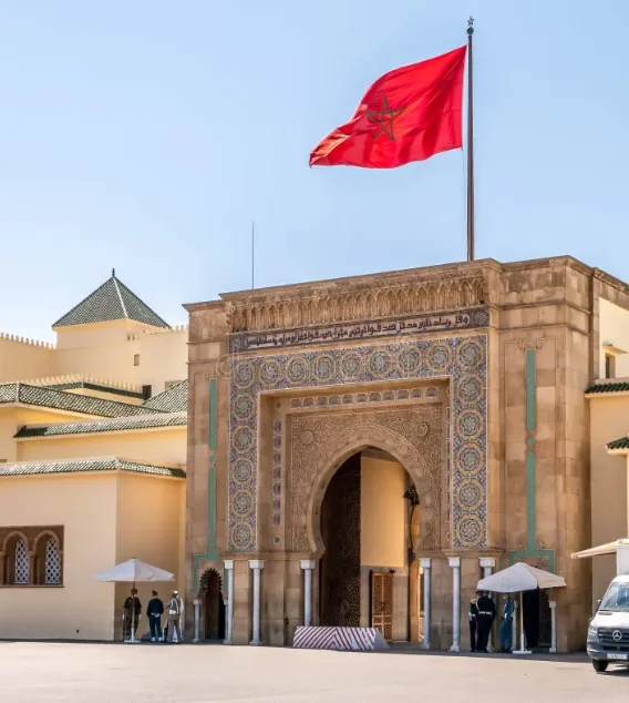 Grande porte d'entrée du palais royal de Rabat surmontée du drapeau du Maroc.