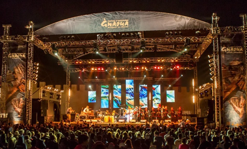 Large Gnaoua Festival concert stage with musicians and a massive crowd