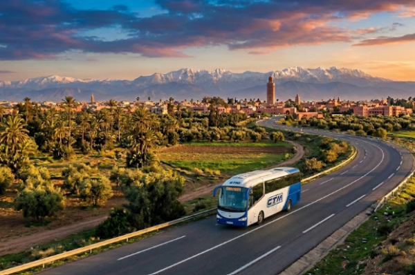 Bus CTM Casablanca Marrakech bleu et blanc roulant sur la route avec en arrière-plan le paysage marocain et l'Atlas.