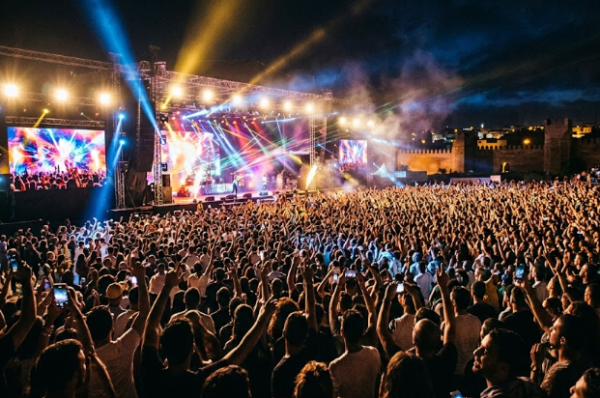 Une foule immense de festivaliers devant la scène géante illuminée de Mawazine 2026 à Rabat à la nuit tombée.