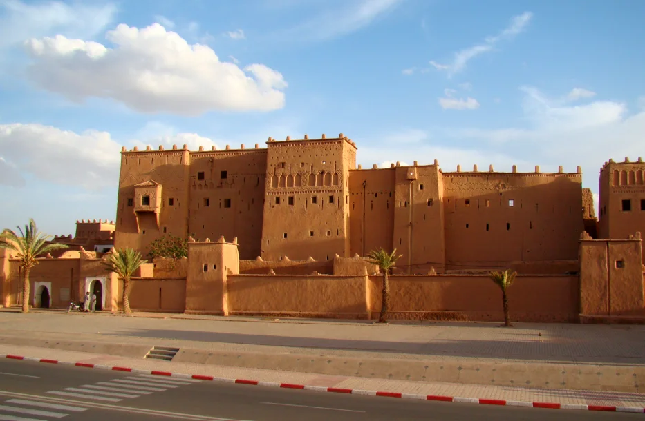 La Kasbah historique de Taourirt à Ouarzazate sous un ciel bleu, une étape culturelle incontournable pour voyager au Maroc.