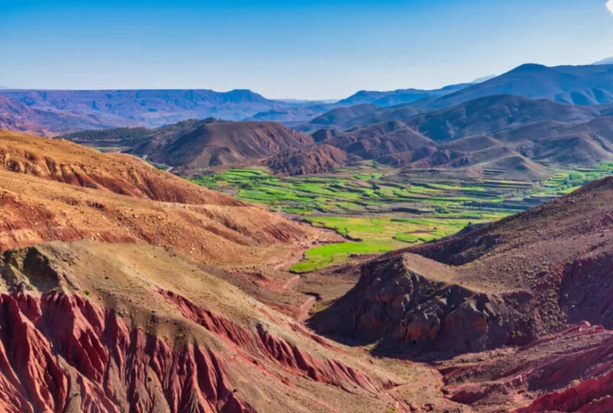 Randonneurs marchant sur un sentier escarpé dans les montagnes de l'Atlas au Maroc avec des sommets rocheux en arrière-plan